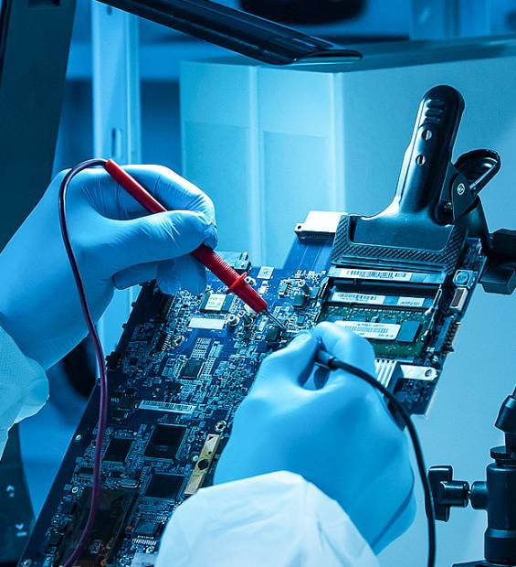 male-technician-testing-circuit-board-multimeter-blue-lighting Technician in blue gloves and lab coat testing microchips on computer circuit board with multimeter under cool blue lighting.